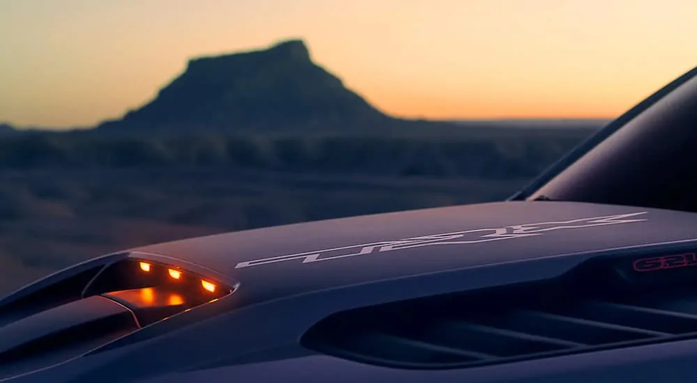 The hood scoop of a silver 2021 Ram 1500 TRX is shown in close up with orange accent lights peeking out.