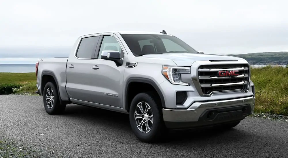 A silver 2020 GMC Sierra 1500 is parked next to a large lake.