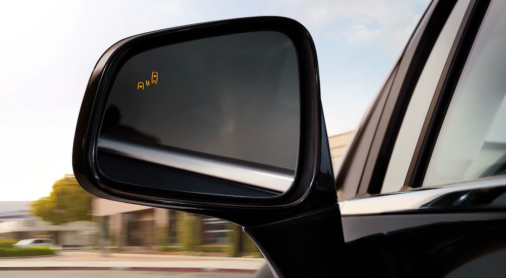 A mirror is shown in close up with an illuminated blind spot monitoring icon on a black 2021 Buick Encore.