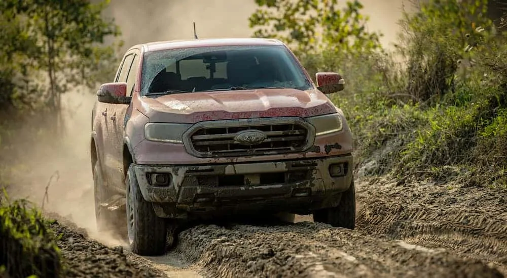 A red 2021 Ford Ranger Tremor Lariat is driving through the mud.