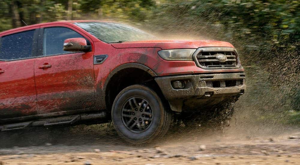A red 2021 Ford Ranger Tremor Lariat is driving through the mud.