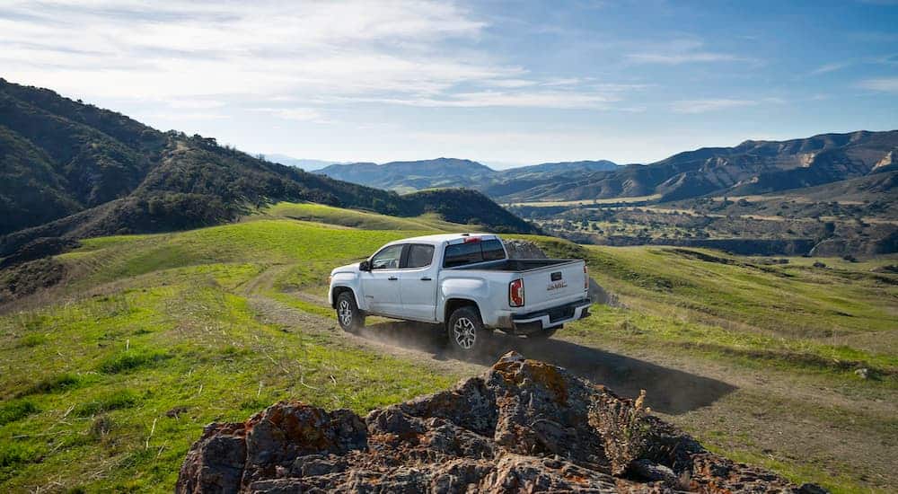 A white 2021 GMC Canyon AT4 is driving in the mountains after the 2021 GMC Canyon vs 2021 Chevy Colorado comparison.