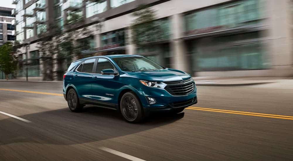 A blue 2021 Chevy Equinox is driving down the road after leaving the Chevy dealer.