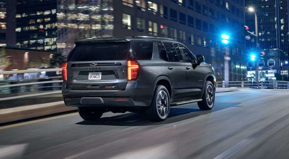A silver 2021 Chevy Tahoe is driving through a city at night.