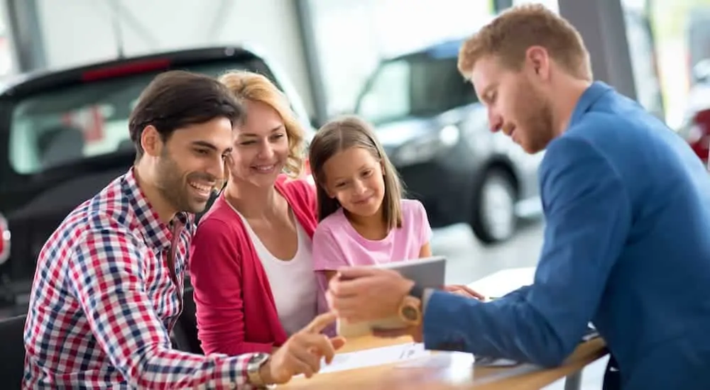 A salesman is helping out a family at a Chevy dealer.