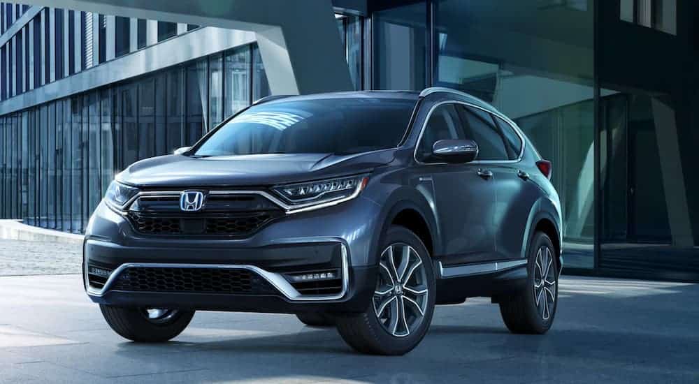 A blue 2020 Honda CR-V Hybrid is parked in front of a modern building after leaving a Honda dealer near you.