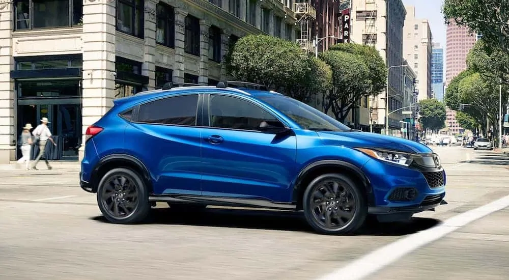 A blue 2021 Honda CR-V is driving down a city street.