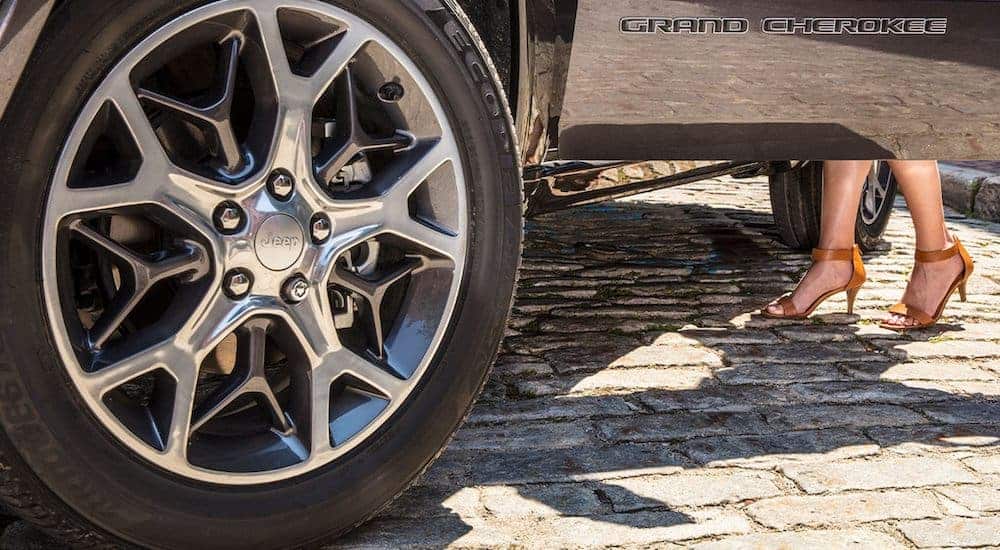 A close up of the badging and wheel is shown on a black 2020 Jeep Grand Cherokee.