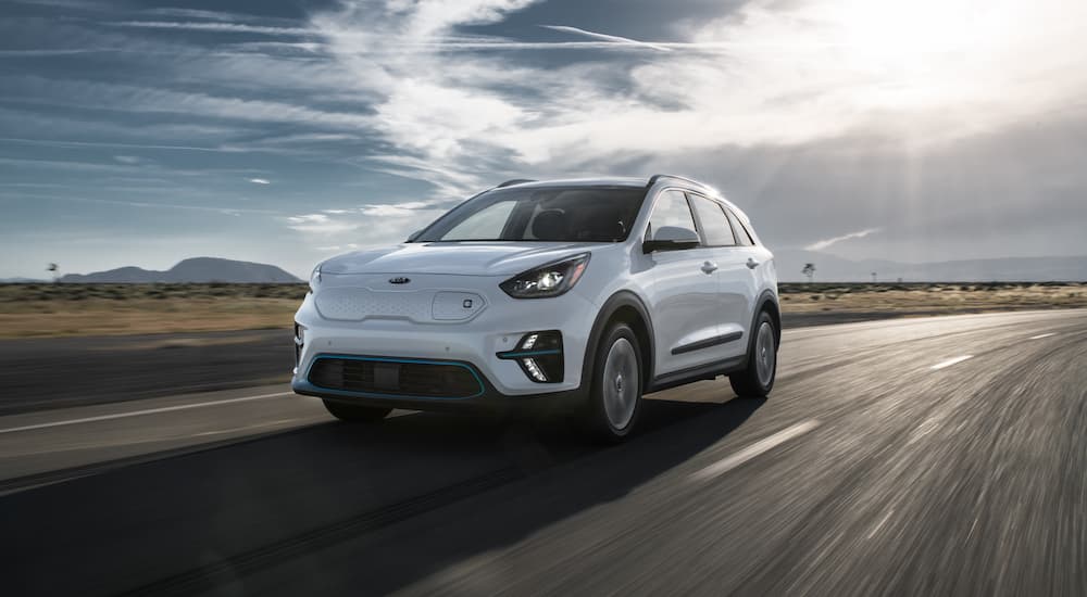 A white 2020 Niro EV is driving down the highway after leaving the Kia dealership.