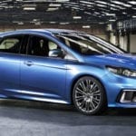 A blue ford model hatchback is shown in a warehouse.