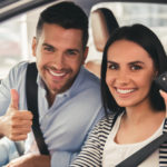 An excited couple giving a thumbs up in their new car