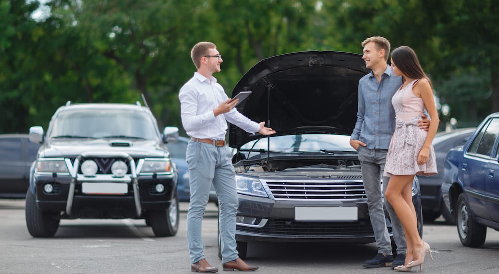 A salesman showing off a used car for sale