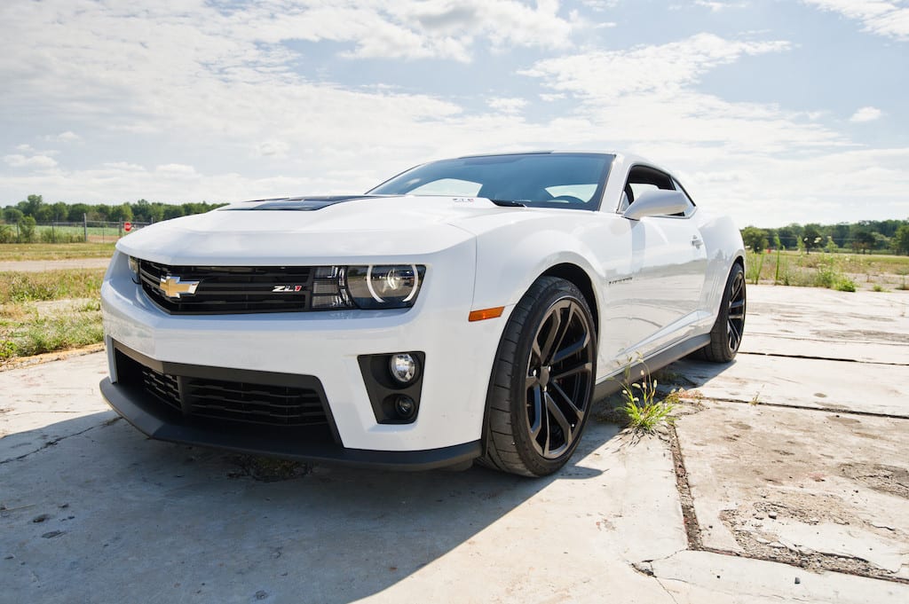 A white zl1 Chevy Camaro with fields in the back