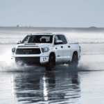 A white 2019 Toyota Tundra TRD Pro is driving in the shallows of the ocean.