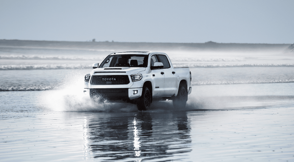 A white 2019 Toyota Tundra TRD Pro is driving in the shallows of the ocean.