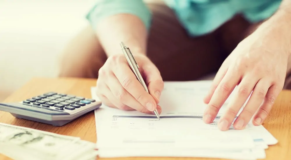 Woman signing a credit report next to a calculator