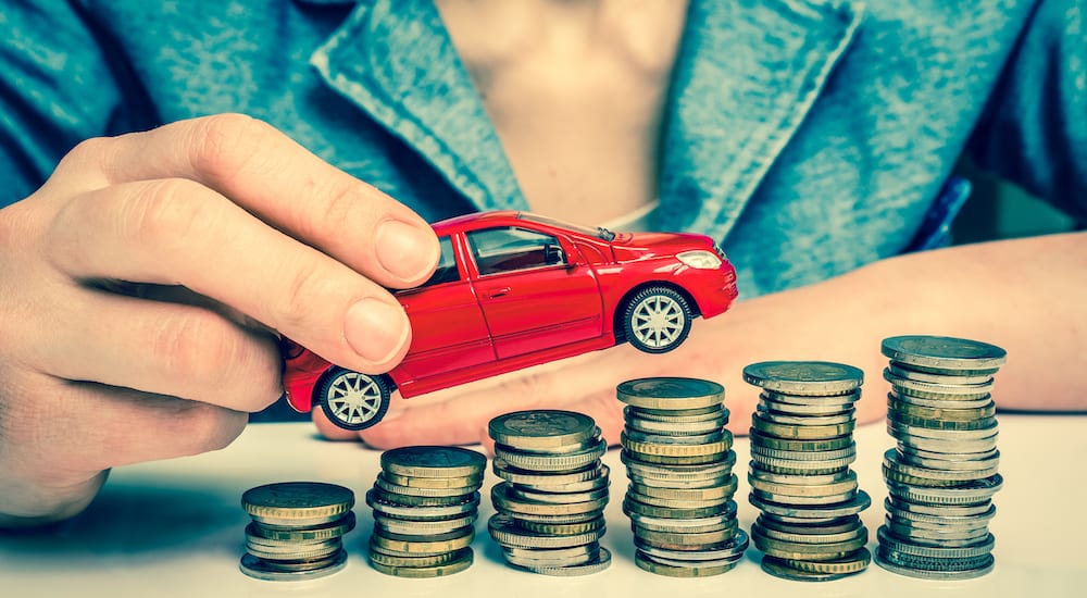 A toy car being raised up a stack of money.