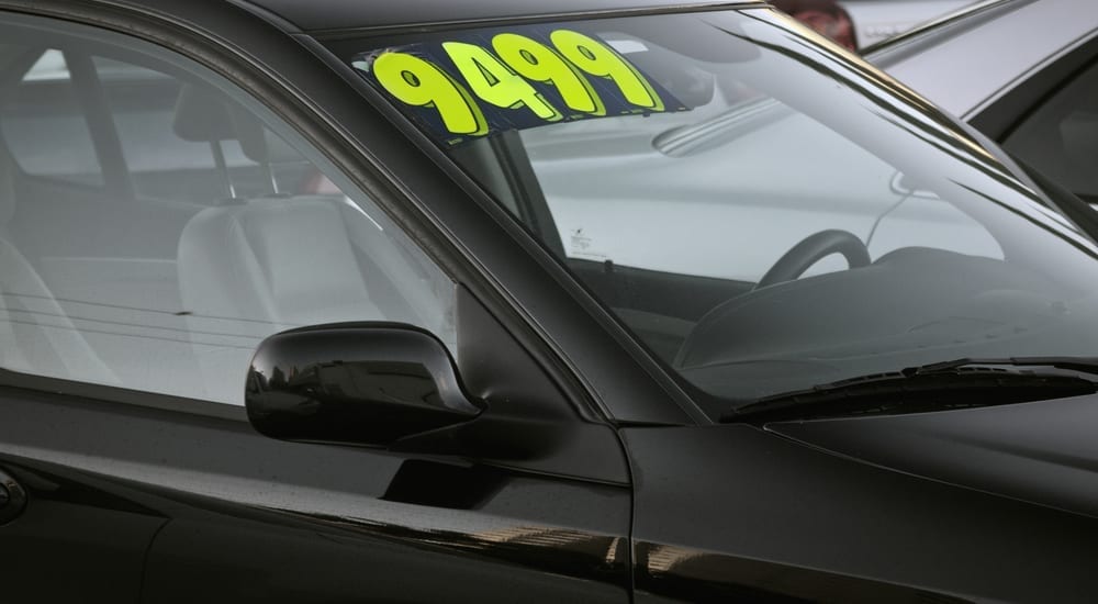 A black car has a price of 9,499 on the windshield at a buy here pay here dealer