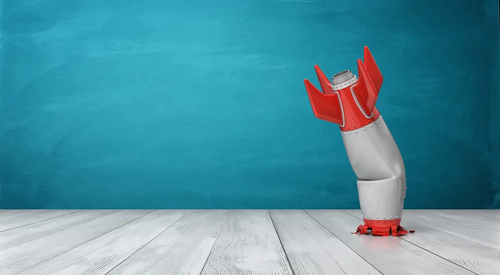 A red and silver toy rocket crashed on a table