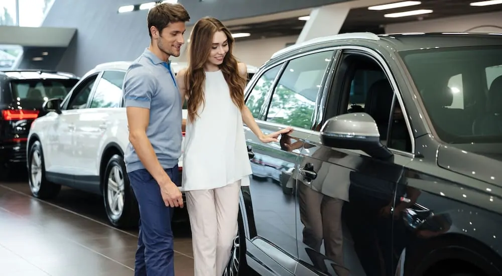 A couple looking at new cars in a modern dealership