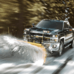 A black Chevy Silverado plowing through snow