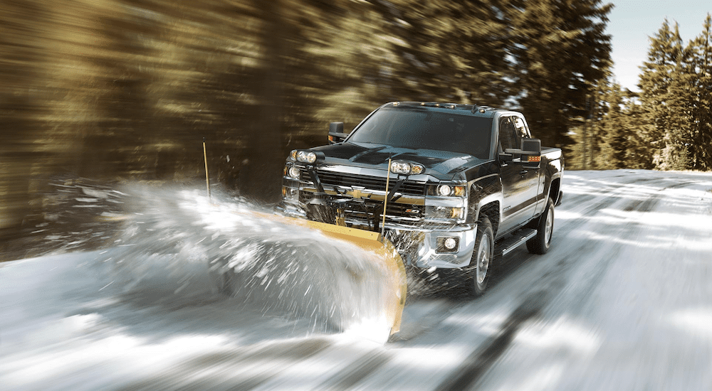 A black Chevy Silverado plowing through snow