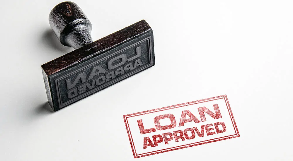 Black stamp laying on its side and red "loan approved" in front of it