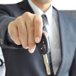 A close-up of a person holding a car key towards the camera.
