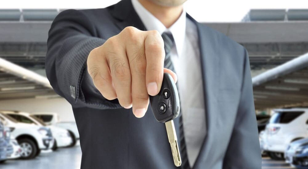 A close-up of a person holding a car key towards the camera.