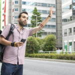 Man hailing and uber in a modern city on the side of the road.