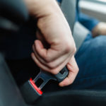 Men's hand fastens the seat belt of the car. Close your car seat belt while sitting inside the car before driving and take a safe journey. Closeup shot of male driver fastens seat belt.