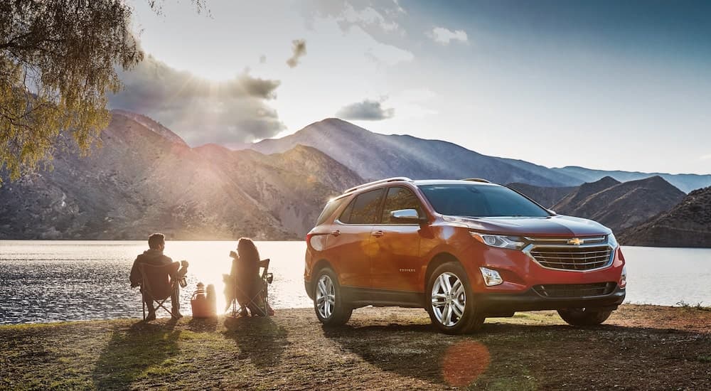 A red 2018 Chevy Equinox is shown parked near a lake in the mountains.