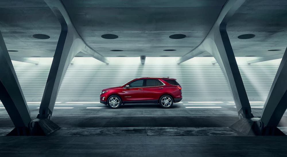 A red 2018 Chevy Equinox is shown from the side in a modern parking garage.
