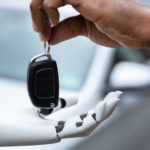 Close up of man handing a white and black robot car keys