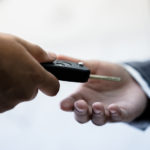 Up close of a man in a suit handing a car key to another man in a suit