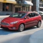 A red Ford Fiesta driving on a city street, get your own with Ford Lease Deals