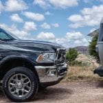 The front of a black Ram 2500HD from your local RAM Dealership next to an Airstream camper against a cloudy and blue desert sky