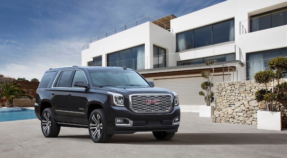 Black 2018 GMC Yukon Denali in front of white mansion and pool