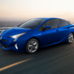 Blue 2018 Toyota Prius on highway with cityscape in background