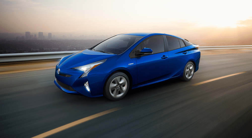 Blue 2018 Toyota Prius on highway with cityscape in background