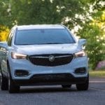 White 2019 Buick Enclave driving down road covered by trees