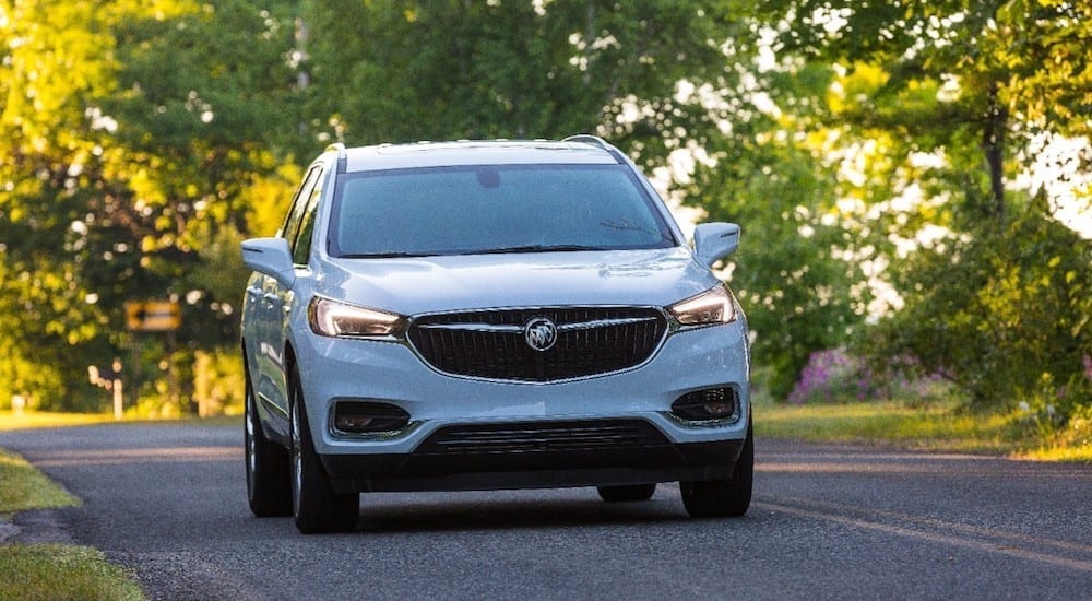 White 2019 Buick Enclave driving down road covered by trees