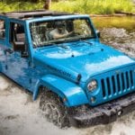 A Blue 2018 Jeep JK crosses a deep river