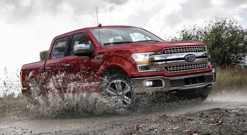 Red 2019 Ford F150 driving through mud