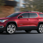 Red 2019 GMC Acadia driving on street