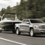 Silver 2019 GMC Canyon Towing boat in front of tree covered hill