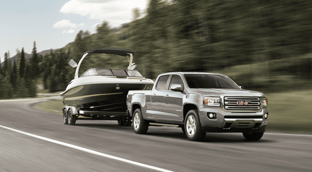 Silver 2019 GMC Canyon Towing boat in front of tree covered hill