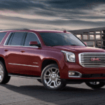 Red 2019 GMC Yukon in front of glass building at sunset