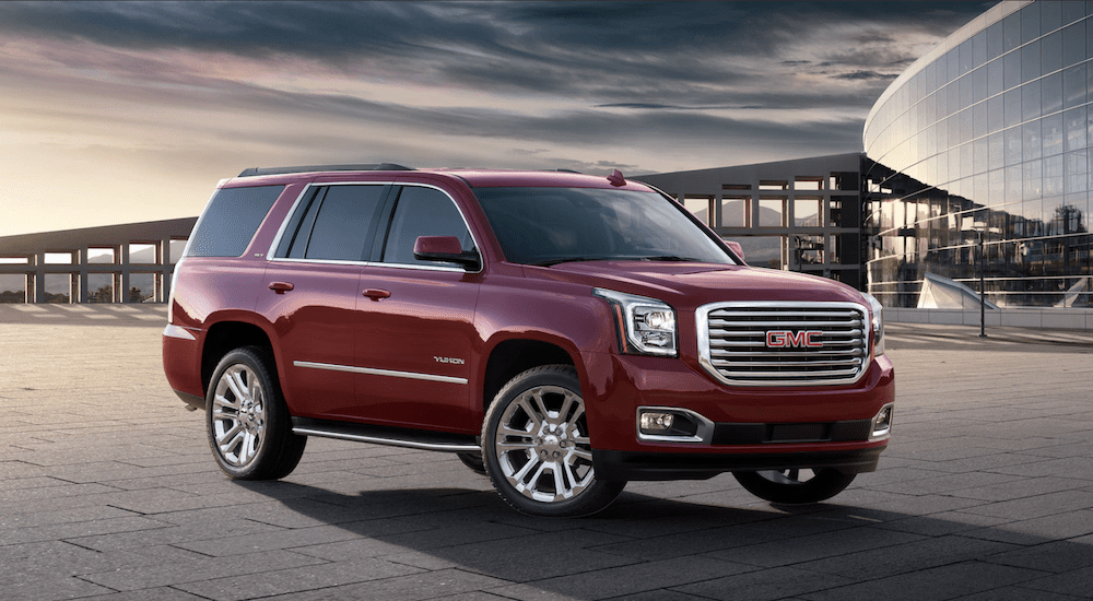 Red 2019 GMC Yukon in front of glass building at sunset