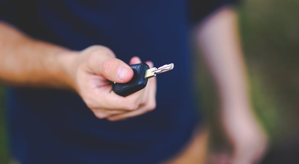 Closeup of hand with car key, rest of body is out of focus